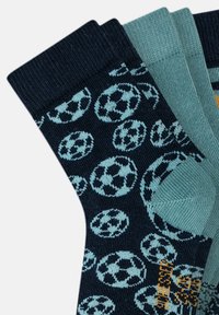 Calze blu navy con un motivo ripetuto di palloni da calcio azzurri, con un accento in verde chiaro e un dettaglio arancione a contrasto.