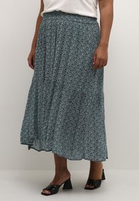 Maxi spódnica w kolorze czarnym i turkusowym, z wzorem paisley, elastycznym pasem i warstwowymi detalami. Połączona z czarnymi, wysokimi klapkami.