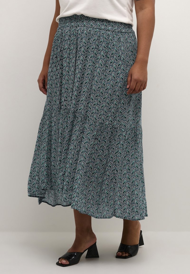 Maxi spódnica w kolorze czarnym i turkusowym, z wzorem paisley, elastycznym pasem i warstwowymi detalami. Połączona z czarnymi, wysokimi klapkami.