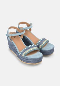 Sandali con zeppa blu e cinturini alla caviglia, caratterizzati da una fascia frontale intrecciata multicolore e da una piattaforma con effetto corda testurizzata.