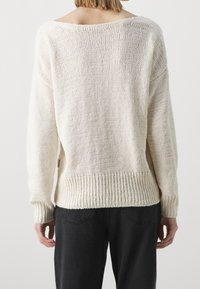 Licht crèmekleurig gebreid sweater met een wijde halslijn en geribde manchetten, met een losse pasvorm en een gestructureerd oppervlak, van de achterkant getoond.