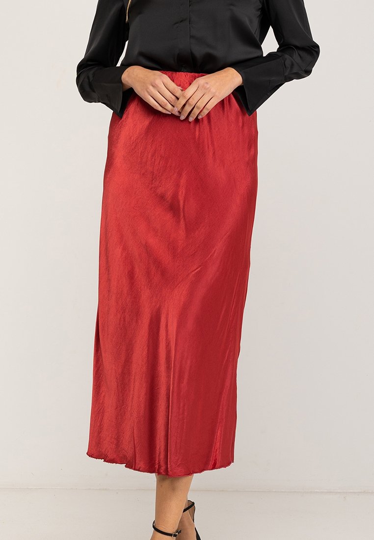 Rode satijnen midi-jurk met een gladde textuur, voorzien van een aansluitende tailleband en een A-lijnvorm, gestyled met een zwarte blouse.