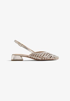 Zapato slingback de tacón bajo en color dorado metálico, con parte superior tejida, correa ajustable con hebilla, punta afilada y tacón de bloque.