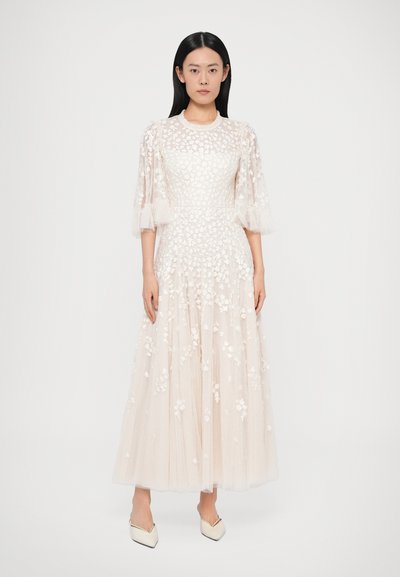 Dlhé, svetlo krémové šaty z priesvitnej látky s kvetinovou výšivkou, krátke volánové rukávy a splývavá, viaczónová sukňa.