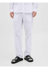 Camisa de lino blanca y pantalones de lino blancos a juego, combinados con sandalias deslizantes negras con detalles grises y dos correas.