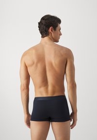 Boxer-briefs bleu marine fabriqués à partir d'un tissu lisse et extensible avec une taille simple ; modèle présenté de dos, avec un minimum de détails.