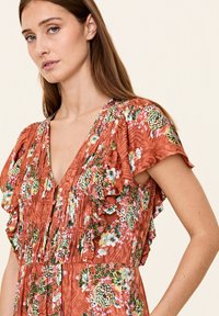 Roestkleurige jurk met bloemenpatronen, volants aan de mouwen, een diepe V-hals en gestructureerde stof met plooien.