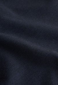 Nahaufnahme von dunkelblauem Stoff mit weichen Falten und glatter Textur.