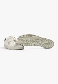 Sneaker bianche con tomaia in pelle liscia e punta in suede grigio. Presentano una suola in gomma con texture a spina di pesce e logo laterale.