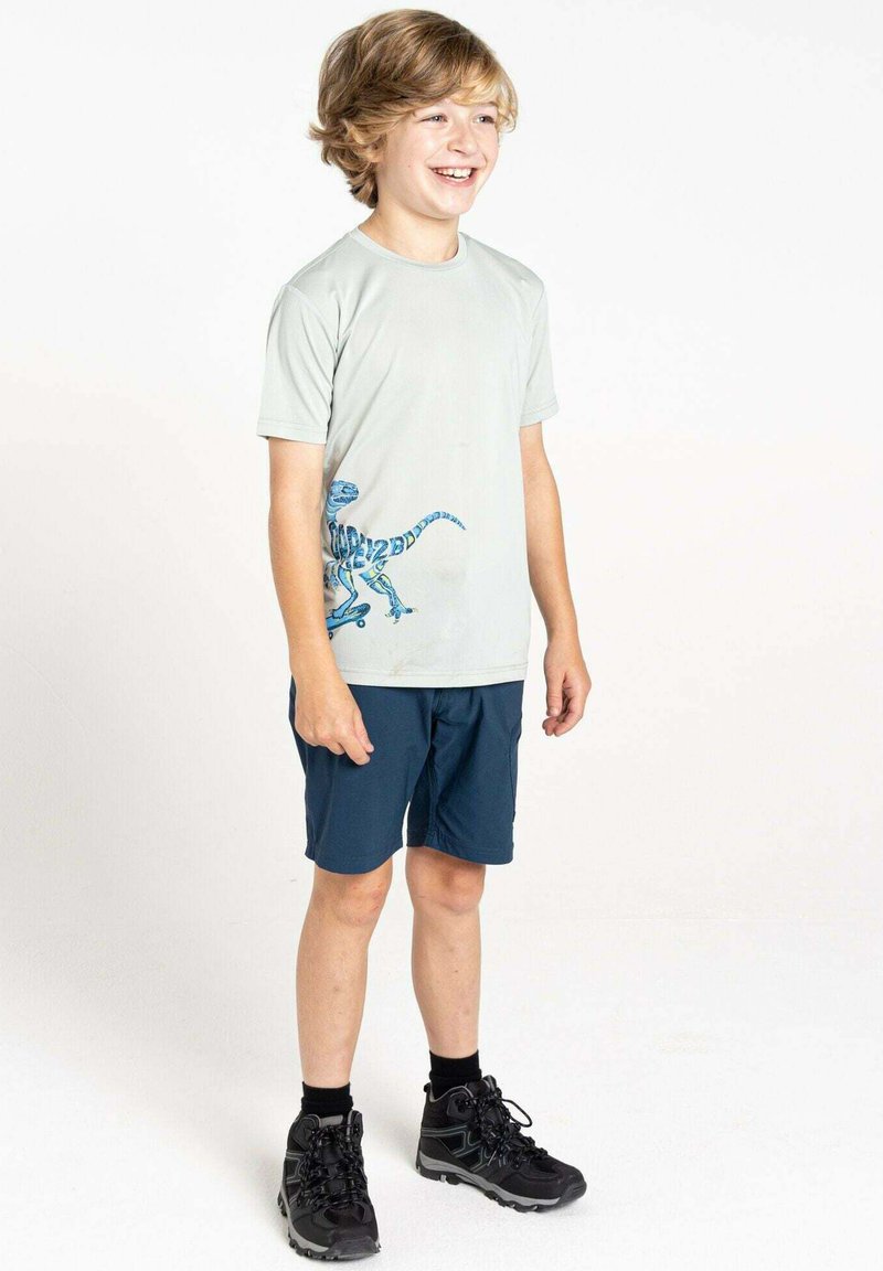 Helle graue Kurzarm-T-Shirt mit einem blauen Dinosaurier-Design, kombiniert mit dunkelblauen Shorts und schwarzen Wanderschuhen, steht vor einem hellen Hintergrund.
