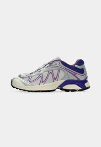 Lightweight athletic shoe in silver and white, featuring purple accents and a textured mesh upper. Rounded toe and rubber outsole.