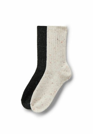 Zwei gestrickte Socken: eine schwarze, eine cremefarbene mit Sprenkeln. Vertikales Rippenmuster; weiche Textur; kontrastierende Farben schaffen einen schlichten, modernen Look.