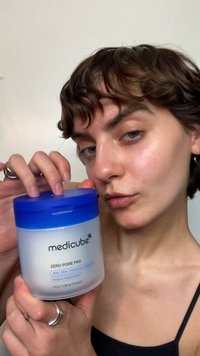 Medicube Zero Pore Pad, in un contenitore rotondo bianco con coperchio blu, che mostra l'etichetta del prodotto. Contiene 70 salviette, con vari ingredienti per la cura della pelle elencati.