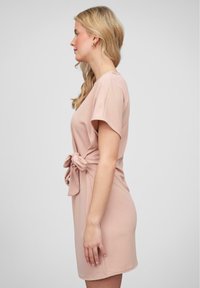Knee-length pink dress made of soft fabric, featuring short sleeves and a tied accent at the waist for added detail.