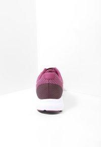 Baskets de sport avec un dessus en maille dans des tons de violet, talon texturé et semelle intermédiaire blanche avec des accents roses. La vue arrière montre un col rembourré.