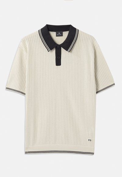Polo majica s kratkimi rokavi v kremni barvi z teksturiranim vzorcem, črnimi ovratnikom in zapenjanjem, ter kontrastnimi črtami. Logo na robu.