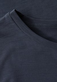 Tmavě modré tričko s kulatým výstřihem a texturovanou látkou s jemnými variacemi v tonálním odstínu.