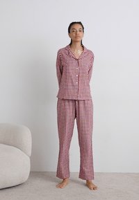 Rød og hvidternet pyjamas sæt lavet af blødt stof; inkluderer en knap-op skjorte og matchende bukser med en afslappet pasform.
