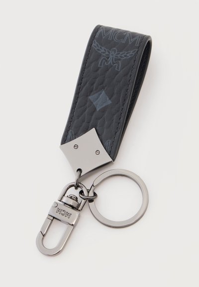 Lanière de porte-clés en cuir noir texturé avec fermoir en métal et anneau pour clés, ornée du logo MCM embossé et de motifs décoratifs.