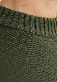 Tamnozeleni pleteni pulover s rebrastim okovratnikom. Materijal izgleda mekano, teksturirano i rastezljivo s glatkom završnom obradom i dosljednim uzorkom.