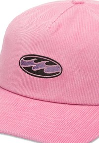 Roze corduroy pet met een zwart en paarse golflogo op een ronde patch. De pet heeft een gestructureerd oppervlak en een gebogen rand.