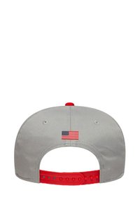 Szara czapka z regulowanym czerwonym paskiem. Z tyłu ma małą haftowaną amerykańską flagę. Gładki materiał, zaokrąglony kształt.