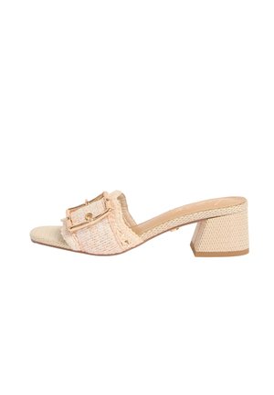 Beige vævet mule sandal med blokhæl og stor dekorativ spænde på bred frontrem.