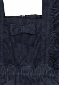 Mörkblå kordklänning med fyrkantig halsringning, som har en central rosettdetalj, samlad midja och sidoflikar. Dragkedja ingår.