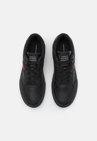 Sneakers in pelle nera con punta rotonda, dettagli traforati, lacci piatti e branding a strisce in rosso e blu. Suola in gomma nera spessa.