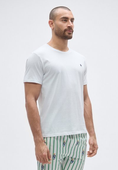 Fehér pamut póló rövid ujjakkal és kerek nyakkivágással, a bal mellrészen kis tengerészkék logóval. Sima textúra, normál szabás.