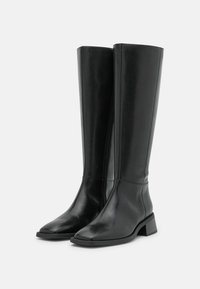 Botas negras hasta la rodilla hechas de cuero liso, con punta cuadrada, un tacón bajo en bloque y una cremallera lateral para ponerlas y quitarlas fácilmente.