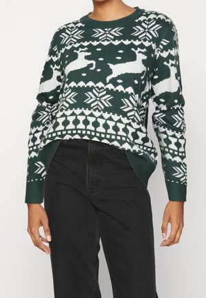 Pull en tricot vert avec des motifs de rennes blancs et de flocons de neige, col et poignets côtelés, avec une coupe décontractée et une texture douce.