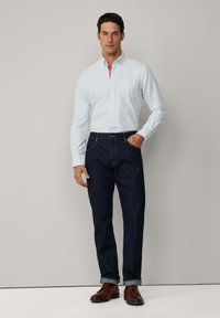 Lichtblauw gestreepte button-up blouse met een borstzak, gecombineerd met donkerblauwe denim jeans en een paar bruine leren schoenen. Eenvoudige, klassieke pasvorm.