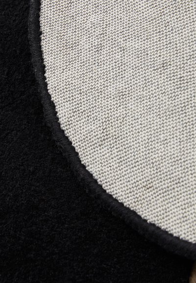 Zwart en grijs textiel met zacht, donzig zwart materiaal en een glad geweven lichtgrijze sectie met een afgeronde rand.