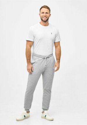 Grijze joggerbroeken met elastische boorden, gecombineerd met een effen wit T-shirt met korte mouwen en een klein zwart logo. Draag ze met witte sneakers.