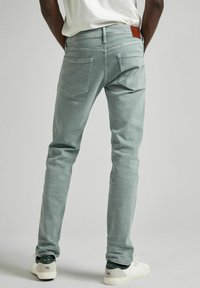 Jeans in denim verde sbiadito con vestibilità slim, cinque tasche e un'etichetta in pelle in vita. Presentano un sottile dettaglio di cucitura sulle tasche posteriori.