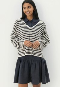 Strikket stribet sweater i creme og marinebl�å med v-hals og brede ærmer, lagt over en mørk knap-op kjole med en udsvajet nederdel.
