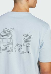 Svetlo modré bavlnené tričko s čiernym kresbou karavanu, osoby, psa a tabuľkami ukazujúcimi vzdialenosť k táboreniu.