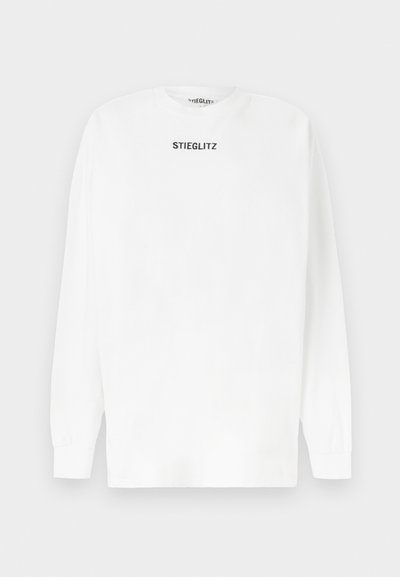 Tricou alb cu mâneci lungi, din bumbac, cu un guler rotund și textul negru "STIEGLITZ" imprimat pe piept. Textură moale.