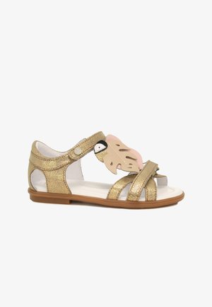 Zlaté třpytivé sandály s růžovým listovým akcentem, otevřenou špičkou, nastavitelným popruhem a bílou vnitřní podšívkou. Plochá podrážka s zaoblenými okraji.