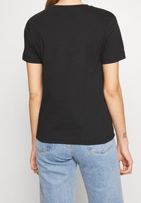 Černé bavlněné tričko s krátkými rukávy a volným střihem. Rovný lem, minimalistické detaily a klasický design s kulatým výstřihem.