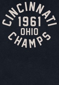 Granatowa koszulka grafika z napisem "CINCINNATI 1961 OHIO CHAMPS" w beżowym, pogrubionym kroju pisma, znajdującym się wyśrodkowanym i łukowato powyżej i poniżej tekstu.