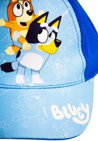 Cani cartoni blu e arancioni che sorridono su un cappellino azzurro chiaro con il testo "Bluey" sul visore.