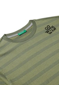 Camiseta de color verde oliva con rayas horizontales, que presenta un patrón texturizado y el texto bordado "VE A TU RITMO" en negro. Tejido de mezcla de algodón.