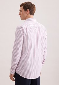 Camicia bianca con righe verticali rosa, maniche lunghe, polsini con bottoni e colletto classico. Tessuto liscio con vestibilità sagomata e orlo arrotondato.