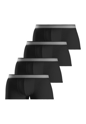 Oberkörper und Beine eines Mannes, der schwarze Boxershorts mit gestreiftem Bund trägt und den Bund mit der linken Hand leicht nach außen zieht.