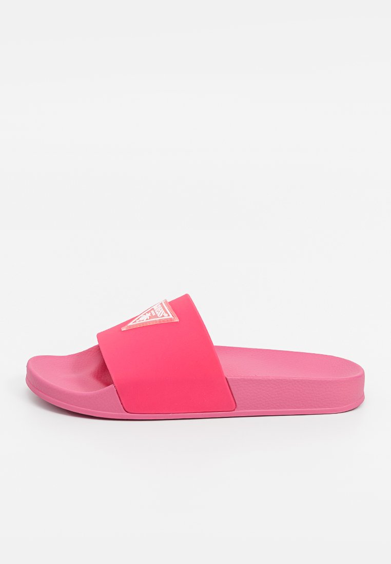 Sandalia de goma rosa con una tiranta ancha, plantilla texturada y un acento de logo en la tiranta. Suela plana y diseño de punta redondeada.