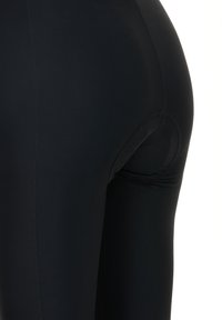 Black leggings with a smooth, stretchy material, featuring a curved seam and a small circular cutout at the back for added detail.