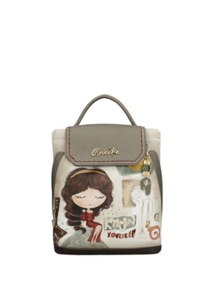 Zainetto piccolo con illustrazione di una ragazza seduta, testo "Conosci te stesso", patta marrone chiaro e ciondoli decorativi appesi sul lato.