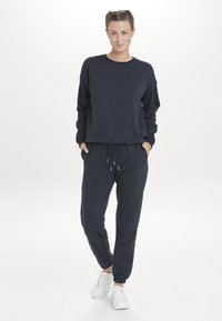 Donkerblauwe sweatshirt en jogger set gemaakt van katoenblend stof; comfortabele pasvorm, trekkoord in de taille, ribgebreide manchetten en enkels.